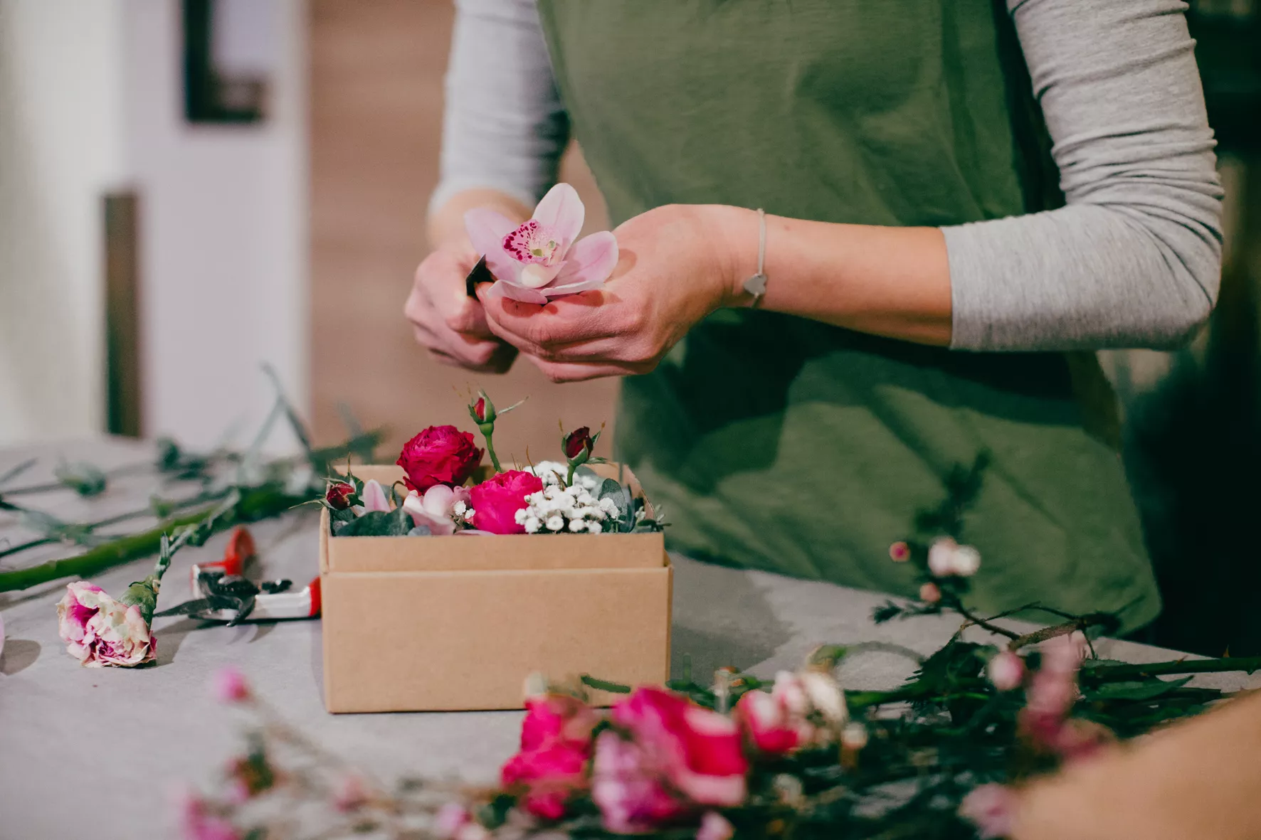 Floristin bereitet eine Blumenbox mit roten und rosafarbenen Blumen vor